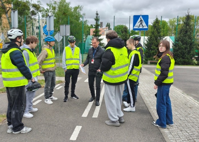 Zdjęcie 6. Uczestnicy „szkolenia praktycznego” na Kartę rowerową na terenie Miasteczka Ruchu Drogowego położonego przy ulicy Gen. K. Sosnkowskiego 10 w Warszawie oraz Pan Sławomir Bakalarski – Egzaminator
z WSiBRD omawiający egzamin. (Zdjęcie źródło: WORD w Warszawie).