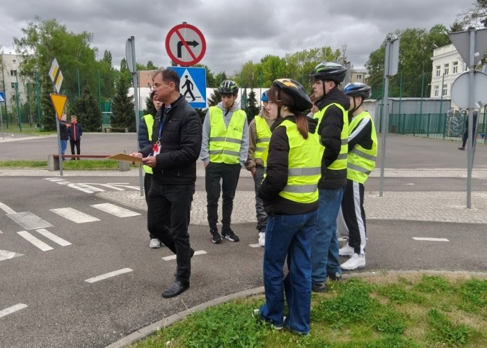Zdjęcie 7. Uczestnicy „szkolenia praktycznego” na Kartę rowerową na terenie Miasteczka Ruchu Drogowego położonego przy ulicy Gen. K. Sosnkowskiego 10 w Warszawie oraz Pan Sławomir Bakalarski – Egzaminator
z WSiBRD omawiający egzamin. (Zdjęcie źródło: WORD w Warszawie).