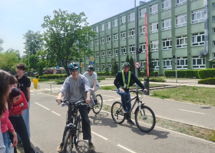 Zdjęcie 2. Uuczniowie I Liceum Ogólnokształcącego im. Maharadży Digvijay Sinhji w Warszawie - uczestnicy „szkolenia praktycznego” na Kartę rowerową oraz Pan Sławomir Bakalarski (w szelkach odblaskowych) – Egzaminator z WSiBRD prowadzący zajecia na terenie Miasteczka Ruchu Drogowego przy ul. Sołtyka 8 w Warszawie. (Zdjęcie źródło: WORD w Warszawie).