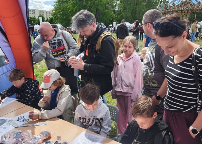 Zdjęcie 3. Najmłodsi uczestnicy Dni Ursynowa 2026 wraz z rodzicami podczas rozwiązywania rebusów i krzyżówek edukacyjnych na stoisku WORD w Warszawie (zdjęcie źródło: WORD w Warszawie).